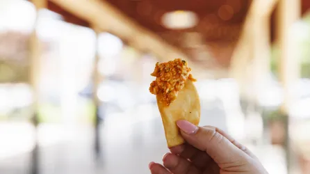 Pimento cheese rests on top of a pita cracker that someone is holding in the air.
