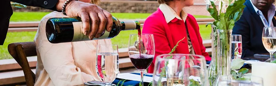 Wine being poured into glass during an event outside in the garden.