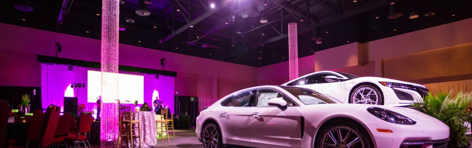 large conference and trade show room with custom lighting and cars on display