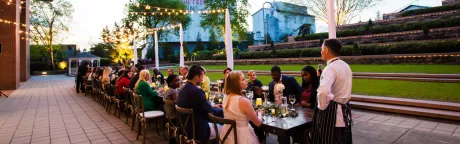 Chef speaking with table of guest at outdoor event.