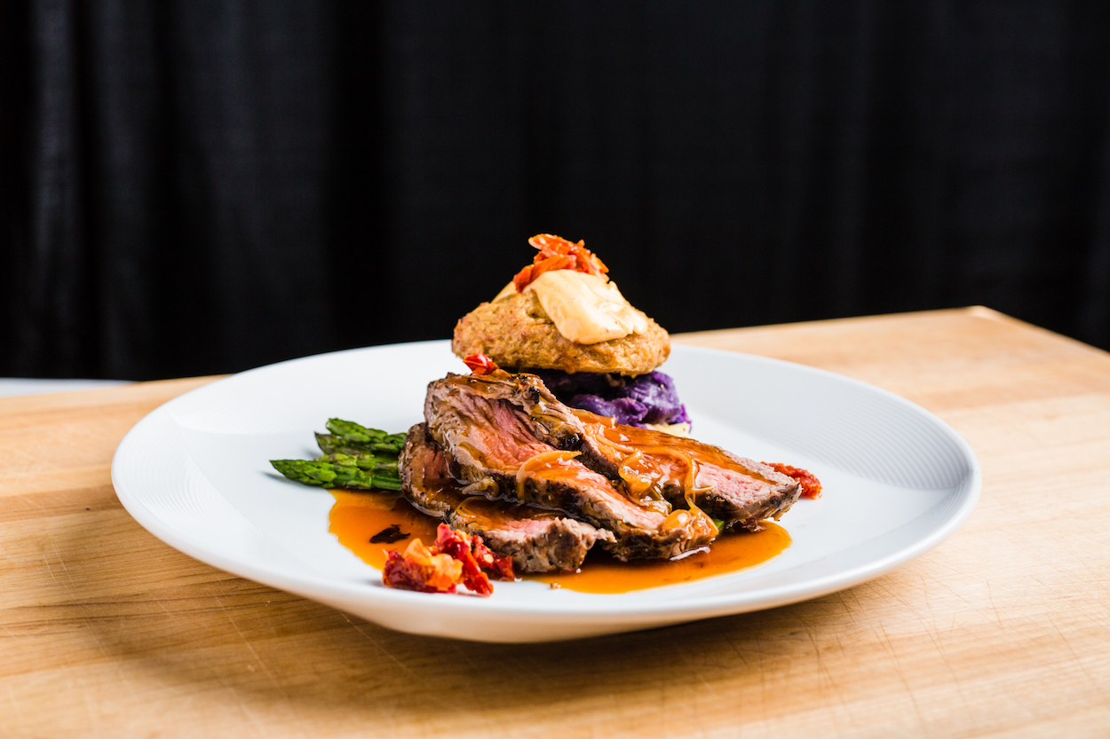 Sliced grilled Teres Major Topped with Caramelized Vidalia Onion Demi, Paired with Lump Style Crab Cake Topped with Spicy Remoulade, Accompanied by a Roasted Medley of Potatoes and Roasted Asparagus